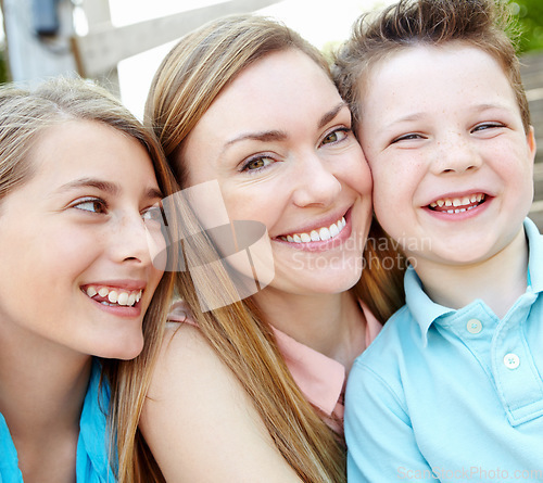 Image of She loves her little ones. Smiling attractive mother embracing her teen daughter and young son while outdoors.