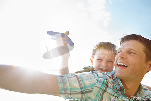 Image of Lets make it soar. A cute little boy playing with an airplane while being carried on his fathers back.