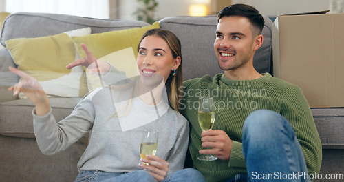 Image of Couple, move and celebration champagne or boxes talking for pointing furniture or living room, chat or happy. Man, woman and new property cheers drink for apartment change achievement, toast or relax
