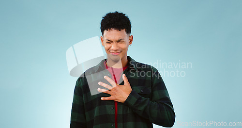 Image of Man, hands or chest pain in studio for heart attack, emergency or cardiovascular risk. Young person, face and anxiety for asthma breathing, tuberculosis and pulmonary embolism by blue background