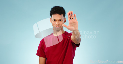 Image of Portrait, man and hand gesture in studio for stop for warning, order or threat on blue background. Isolated model, palm or body language with attention, danger or protest for protection or safety