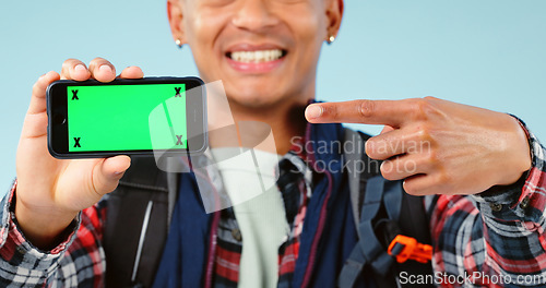 Image of Hands, point and phone with green screen in studio for hiking app, travel mockup and space by blue background. Person, smartphone and chromakey with tracking markers, promotion and user experience