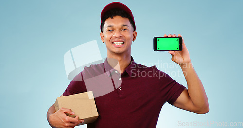 Image of Courier man, phone and green screen in studio for smile, mockup space or box by blue background. Supply chain expert, cardboard package and smartphone for app promotion, chromakey or tracking markers