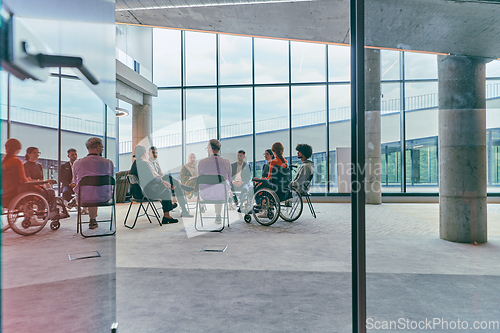 Image of A diverse group of young business entrepreneurs gathered in a circle for a meeting, discussing corporate challenges and innovative solutions within the modern confines of a large corporation