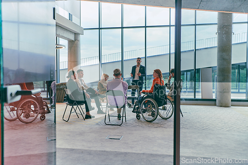 Image of A diverse group of young business entrepreneurs gathered in a circle for a meeting, discussing corporate challenges and innovative solutions within the modern confines of a large corporation