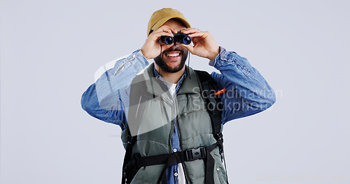 Image of Hiking, backpack and happy man with binocular search in studio for travel, freedom or adventure on grey background. Camping, journey and backpacker with explore equipment for bird watching in nature