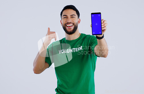 Image of Green screen, phone and thumbs up by volunteer man portrait in studio with news on grey background. Smartphone, space and face of male activist with thank you emoji for charity, donation or support