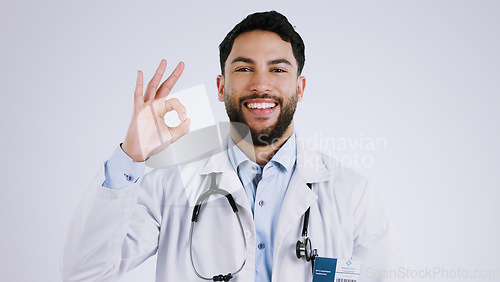 Image of Happy man, portrait and doctor with OK sign for healthcare approval against a gray studio background. Face of male person or medical professional smile with like emoji, okay or yes for perfect health