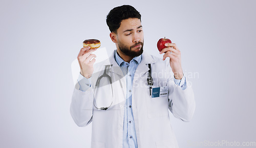Image of Healthy, diet and doctor with choice of food, apple or donut in hands for nutrition in studio white background. Nutritionist, thinking and man with a decision for health with fruit and dessert