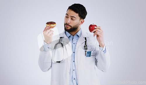 Image of Doctor, apple or donut for choice in health for nutrition in studio on white background for mock up. Man, male model or medical professional with thinking of diet, food or offer for eating in Mexico