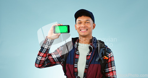 Image of Hiking, green screen and man with a smartphone, portrait and backpack on a blue studio background. Person, hiker and model with mockup space, digital app and cellphone with tracking markers or travel