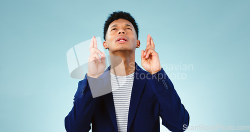 Image of Man, fingers crossed or good luck in studio for prize, promotion or competition giveaway by blue background. Model, hope and emoji for wish for blessing, nervous and waiting for results in mockup