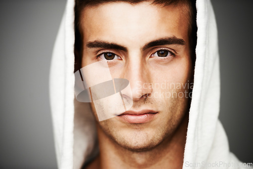 Image of Confident, portrait and man in hoodie for fashion isolated on a gray background. Serious young person, face of model and streetwear clothes, casual and cool facial expression in Spain on a backdrop