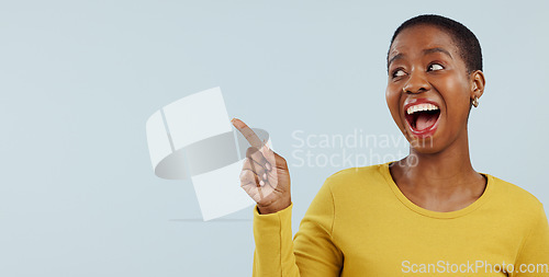 Image of Happy black woman, pointing and surprise for advertising or marketing against a gray studio background. Face of excited African female person smile in wow deal, sale promotion or discount on mockup