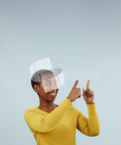 Image of Mockup, smile and black woman with hand pointing up in studio for presentation on grey background. News, announcement and African female model show feedback, checklist or schedule, promo or platform