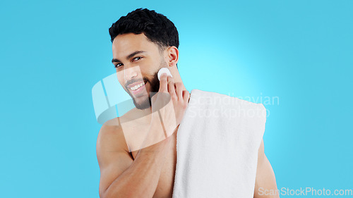 Image of Skincare, portrait and happy man with cotton pad in studio for luxury, grooming or wellness on blue background. Face, smile and model with facial swab for cleaning, cosmetics or after shower beauty