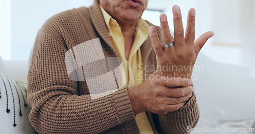 Image of Hand, wrist pain and injury with an elderly person on a sofa in the living room of a home to massage a joint. Medical, anatomy or ache and a senior in his apartment with arthritis or carpal tunnel