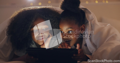 Image of Sisters, girl or tablet at night with internet for movie, cartoon or streaming with blanket on bed in bedroom. Family, kids or children with technology in the dark for film, video and bonding at home