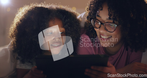 Image of Mother, daughter and tablet at night with internet for movie, cartoon or streaming with blanket on bed in bedroom. Family, woman and girl child with technology in the dark for film, video and bonding