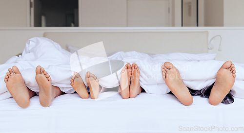 Image of Family, feet and bed with blanket for sleeping, relaxing or rest together with calm and peace in home. People, parents and children with duvet in morning on vacation, holiday or hotel on weekend