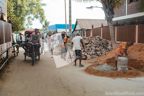 Image of Malagasy men working hard, manually carrying construction stones. Morondava, Madagascar