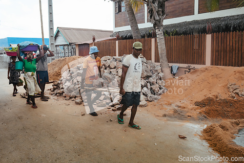 Image of Malagasy men working hard, manually carrying construction stones. Morondava, Madagascar