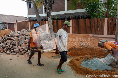 Image of Malagasy men working hard, manually carrying construction stones. Morondava, Madagascar