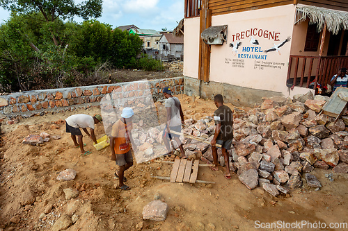 Image of Malagasy men working hard, manually carrying construction stones. Morondava, Madagascar