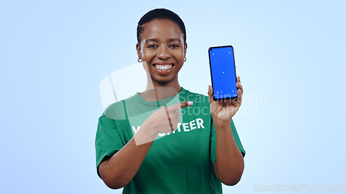 Image of Woman, volunteering and point at phone with green screen in portrait for mockup on blue background in studio. Black person, happy or smile for internet, cellular or network for homepage on mobile app