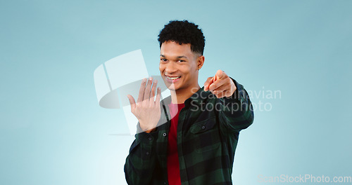 Image of Man, pointing and invitation for welcome in studio, offer and choice on blue background. Model, happy face and hand gesture for sign up in promotion, deal opportunity and advertising for mockup space