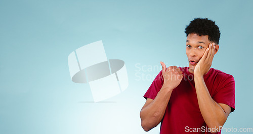 Image of Excited, man and pointing to announcement in studio with gossip, news or portrait in blue background with information. Confidential, secret and promotion of drama, story or emoji for surprise