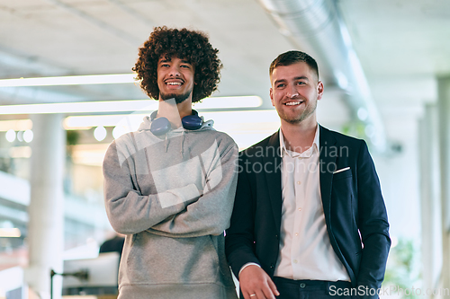 Image of In a modern startup office setting, a business director and a young African American entrepreneur sit surrounded by their colleagues, embodying diversity and teamwork in the corporate world.