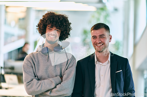 Image of In a modern startup office setting, a business director and a young African American entrepreneur sit surrounded by their colleagues, embodying diversity and teamwork in the corporate world.