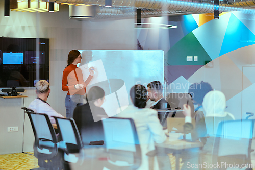 Image of A pregnant business woman with orange hair confidently presents her business plan to colleagues in a modern glass office, embodying entrepreneurship and innovation