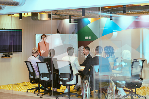 Image of A pregnant business woman with orange hair confidently presents her business plan to colleagues in a modern glass office, embodying entrepreneurship and innovation