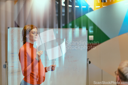 Image of A pregnant business woman with orange hair confidently presents her business plan to colleagues in a modern glass office, embodying entrepreneurship and innovation