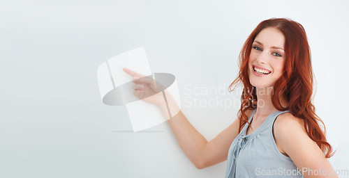 Image of Portrait, happy woman and smile for pointing in studio for presentation mockup for on white background in Ireland. Female model, expression or excitement on face for announcement, offer or promotion