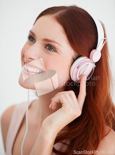 Image of Smile, headphones and young woman in a studio listening to music, playlist or album. Happy, excited and female model from Canada streaming a song, podcast or radio isolated by white background.