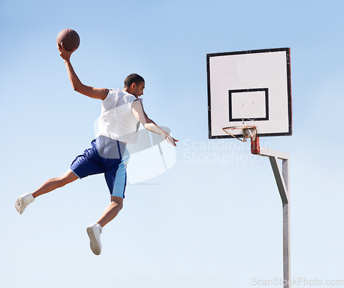 Image of Man, basketball and dunk jump on outdoor court for scoring point, game challenge or athlete. Male person, hand and hoop strong for exercise fun or fitness training in summer, player for winner match