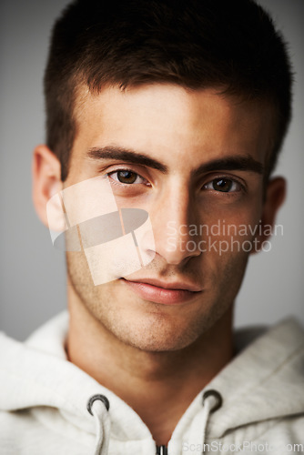 Image of Portrait, confident and man in hoodie for fashion isolated on gray studio background. Serious young person, face of model and clothes, casual style and cool student in trendy streetwear in Spain