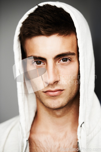 Image of Serious, portrait and man in hoodie for fashion isolated on a gray background. Confident young person, face of model and streetwear clothes, casual and cool facial expression in Spain on a backdrop