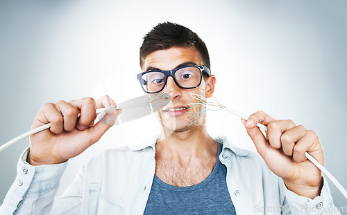 Image of IT support, cable and power with an electrician man in studio on a gray background for troubleshooting. Face, hands and glasses with an engineering nerd or technician connecting wires for internet