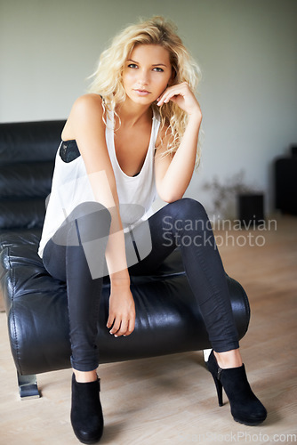 Image of Woman, portrait and fashion with chair for pose in home with casual, trendy or modern for style. Sweden, model and edgy clothes with hand, gesture and serious expression for confidence in living room