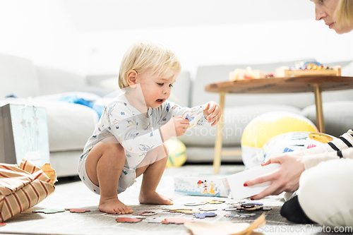 Image of Parents playing games with child. Little toddler doing puzzle. Infant baby boy learns to solve problems and develops cognitive skills. Child development concept