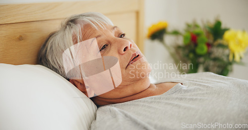 Image of Depression, tired and an elderly woman in bed for peaceful rest or to relax in her retirement home closeup. Face, morning or insomnia with a senior person exhausted in the bedroom of an apartment