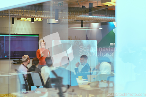 Image of A pregnant business woman with orange hair confidently presents her business plan to colleagues in a modern glass office, embodying entrepreneurship and innovation