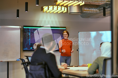 Image of A pregnant business woman with orange hair confidently presents her business plan to colleagues in a modern glass office, embodying entrepreneurship and innovation