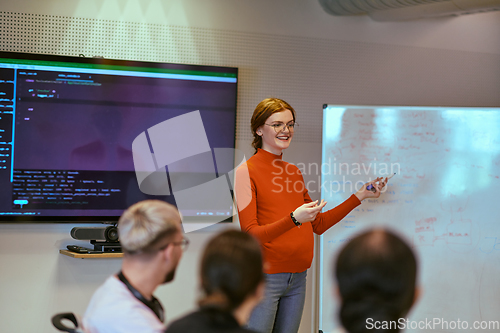 Image of A pregnant business woman with orange hair confidently presents her business plan to colleagues in a modern glass office, embodying entrepreneurship and innovation