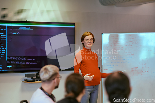 Image of A pregnant business woman with orange hair confidently presents her business plan to colleagues in a modern glass office, embodying entrepreneurship and innovation