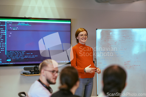 Image of A pregnant business woman with orange hair confidently presents her business plan to colleagues in a modern glass office, embodying entrepreneurship and innovation